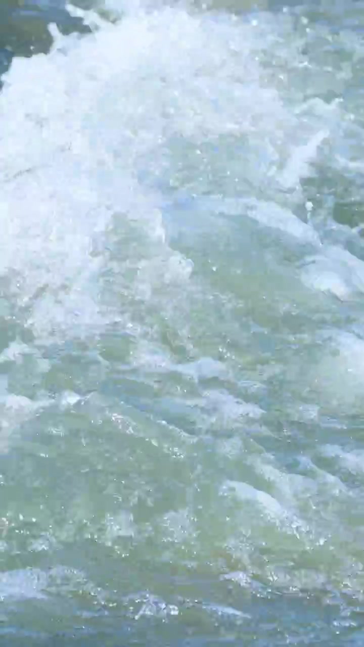 Acqua vibrante e in rapido movimento ripresa nel torrente Glenorchy, che mostra energia naturale e movimento fluido sotto la luce intensa del giorno.