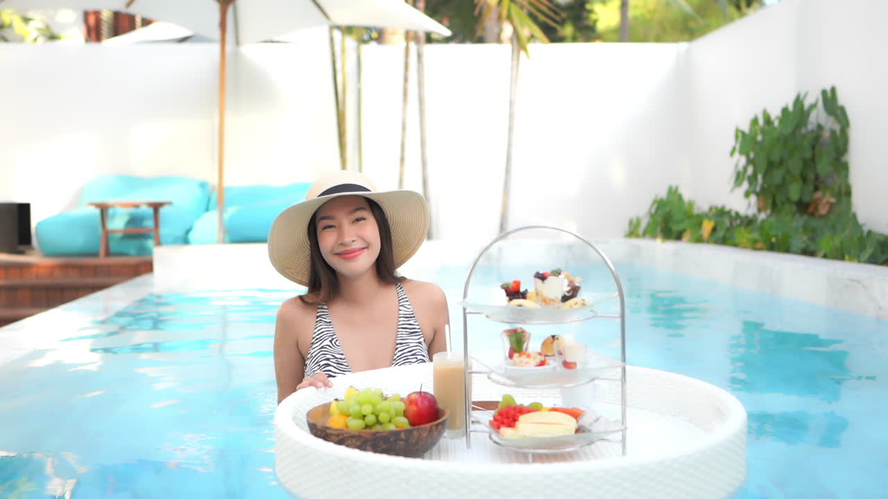 Rich morning breakfast floating table at pool with asian posing