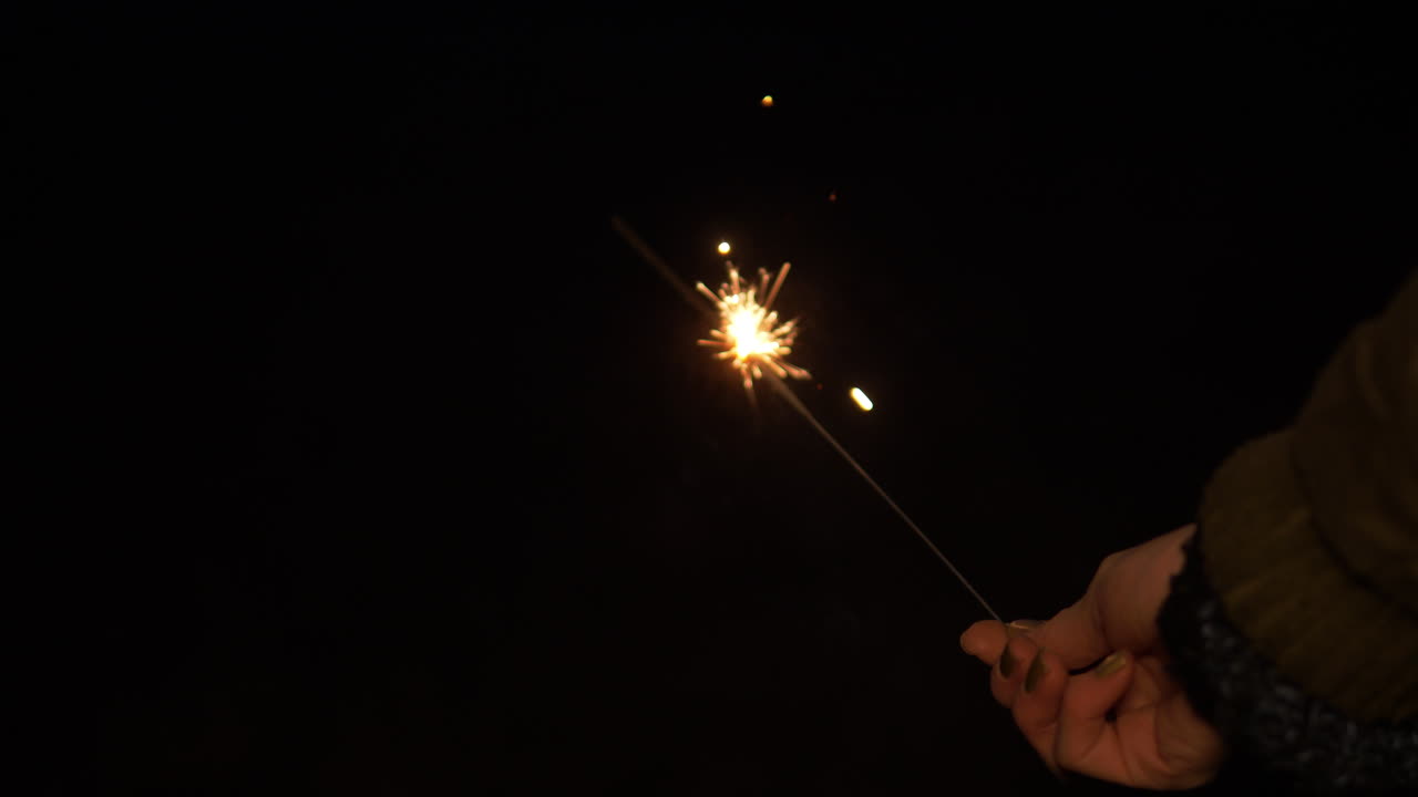 mano de mujer sosteniendo un brillante candelabro de hadas en la víspera de año nuevo