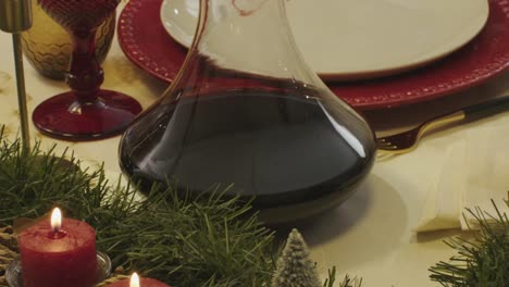festive dining table with a wine decanter, candles, and red glassware