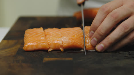 slow motion close up of male chef cutting fresh salmon fillet in several pieces