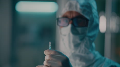 a person in a protective suit holding a syringe in a laboratory setting