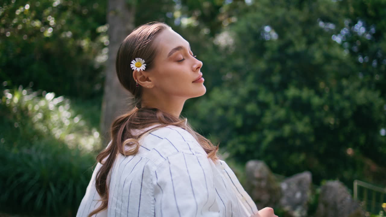dama relajándose en un parque soleado de pie en un primer plano de vegetación. mujer posando bosque verde