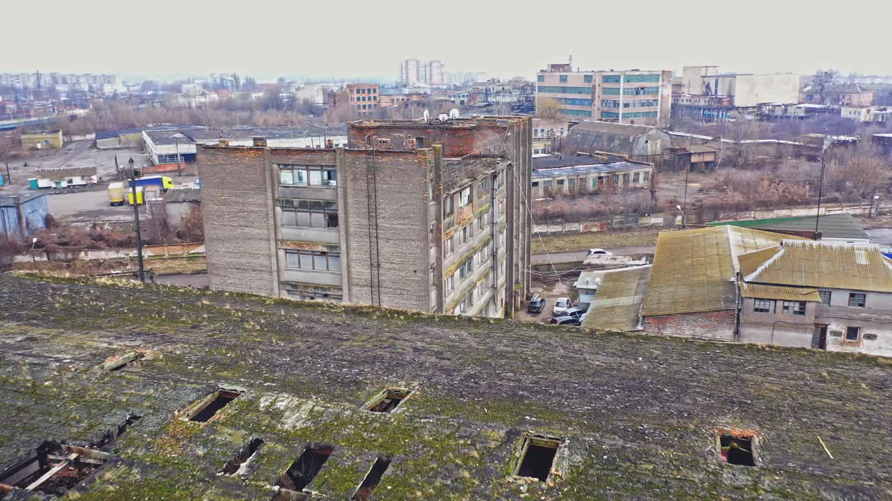Almost destroyed building with holey roof in the city. Top view of ruined industrial building and some cars on a road. Aerial view