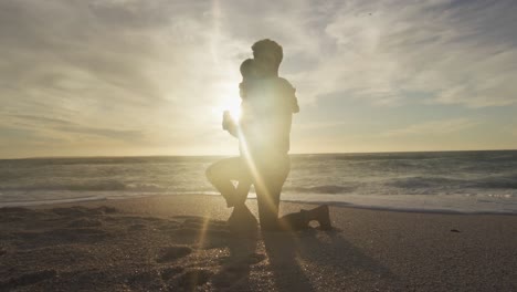 Hispanic-father-embracing-son-on-beach-at-sunset