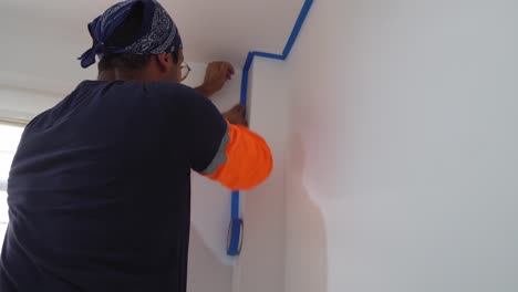 man uses blue painter's tape for diy home painting