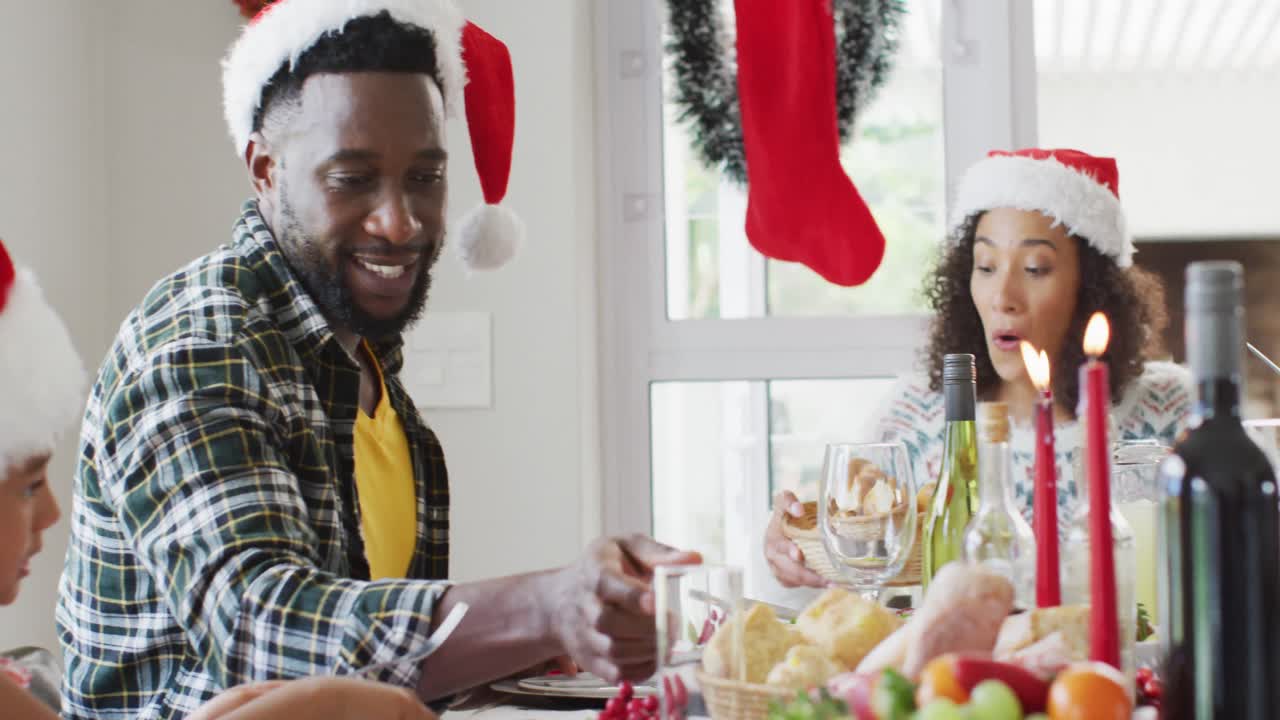 feliz familia afroamericana de varias generaciones con sombreros de papá noel y celebrando en la cocina