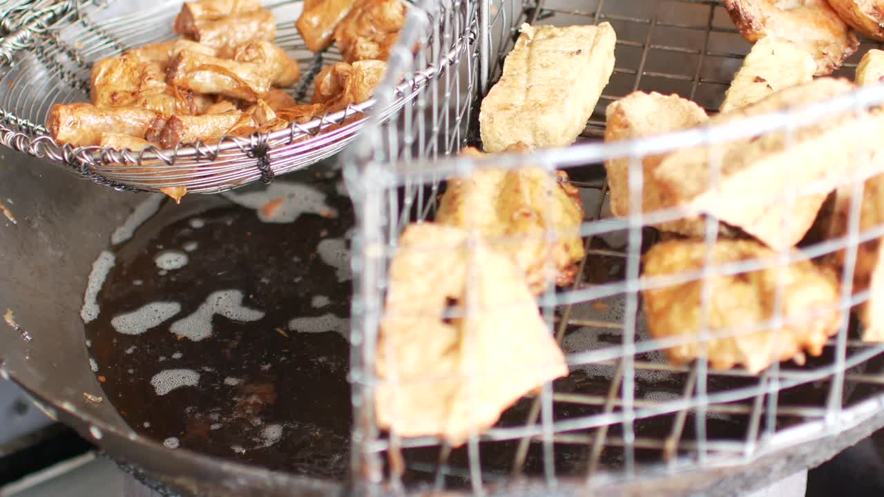 POV into the deep fried pan with freid tofu and spring roll for appetizer