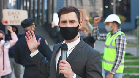 close-up view of caucasian journalist or correspondent wearing protective mask giving interview in a protest against covid 19