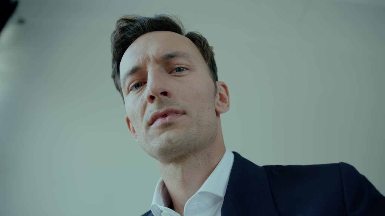 primer plano desde abajo de la cara de un joven de traje con expresión enojada