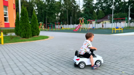 adorable smiling kid riding a toy car outdoors. happy toddler spending time near playground in summer.