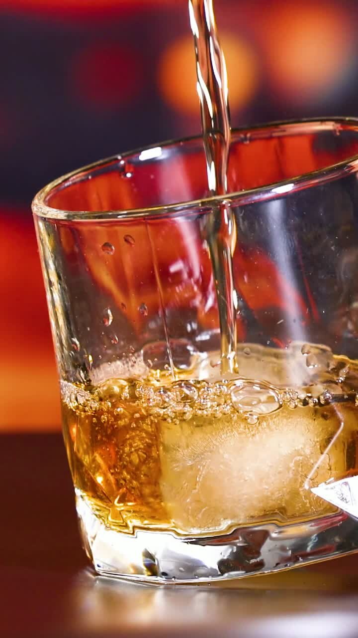Whisky being poured over ice in glass