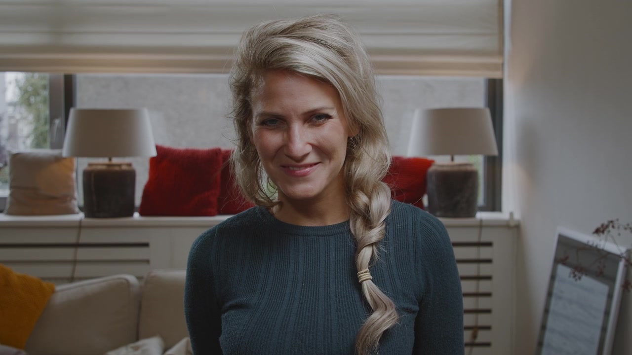 Portrait of a young woman smiling and flirting with the camera in a modern clean living room apartment home