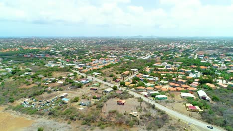 4k-drone-aerial-cinematic-of-neighborhoods-and-houses-in-an-urban-rural-area-of-the-Caribbean-island-of-Curacao,-road-with-cars-driving-below