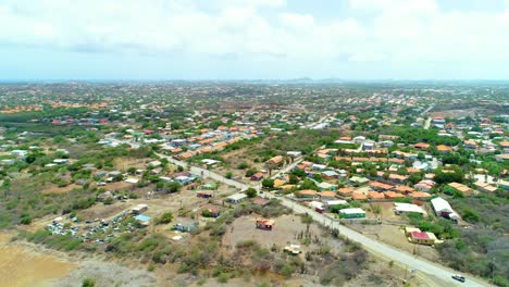 Cine-Aéreo-De-4k-Drones-De-Barrios-Y-Casas-En-Una-Zona-Rural-Urbana-De-La-Isla-Caribeña-De-Curacao,-Carretera-Con-Autos-Conduciendo-Debajo