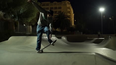 skateboarder doing tricks at a skate park at night