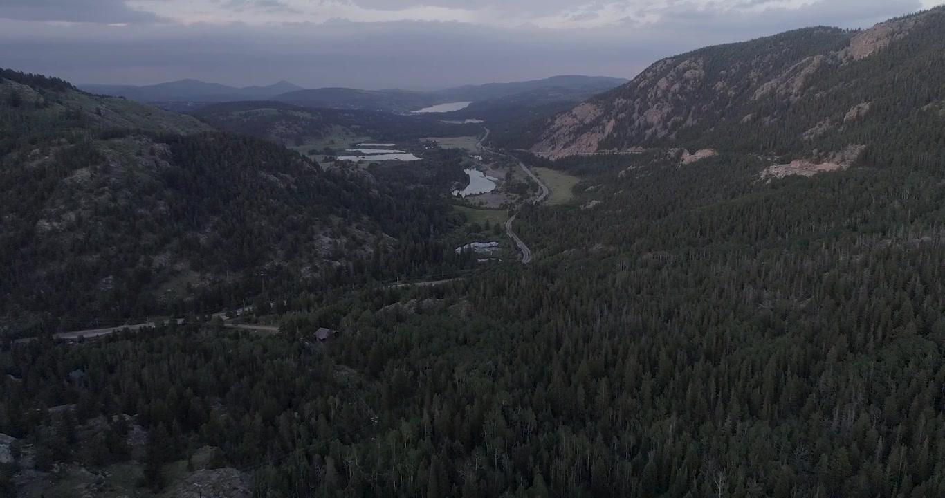 Volo su foreste in una valle aperta in Colorado, paesaggi montani di una cittadina del Colorado, e una prospettiva aerea degli alberi lungo la strada che attraversa la valle