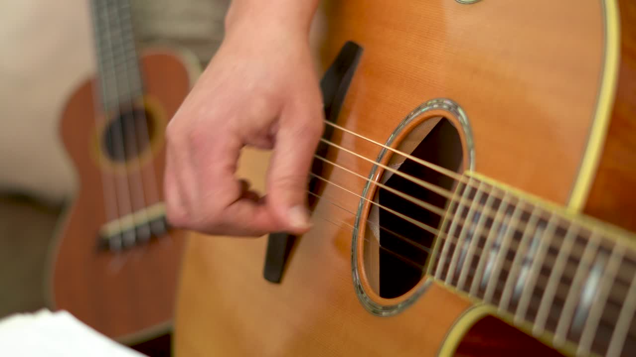 manos masculinas cercanas tocando la guitarra acústica.