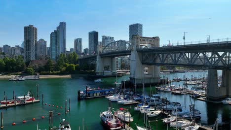 flying over the boats moored in the marina under the burrard street bridge towards downtown vancouver in canada