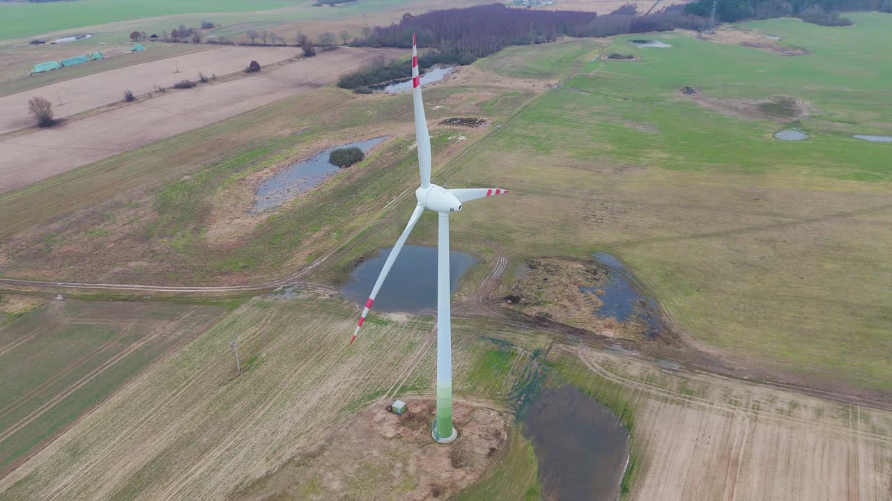 Volo di drone verso una turbina eolica in funzione con pale rotanti.