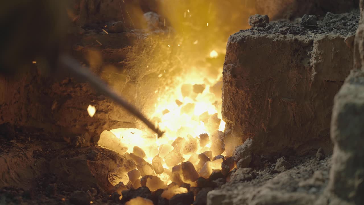 대장장이는 철 단조 작업장에서 불에서 뜨거운 금속을 꺼냅니다.