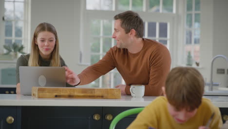 parents helping son and teenage daughter with homework sitting in kitchen at home - shot in slow motion