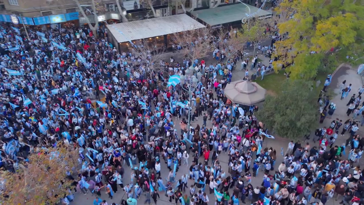 Grande celebrazione pubblica riempie Plaza 25 de Mayo, San Juan, Argentina, con folle che sventolano bandiere argentine, drone in discesa dall'alto.