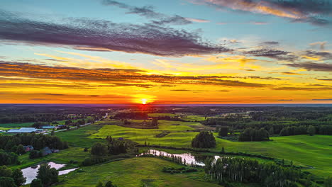 Bright,-colorful-sunset-in-a-rural-landscape-with-the-sky-reflecting-off-pond-water---pullback-aerial-hyper-lapse