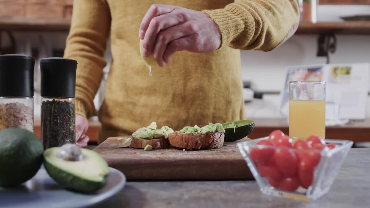 Torso de hombre caucásico preparando tostada de aguacate en la cocina, cámara lenta.