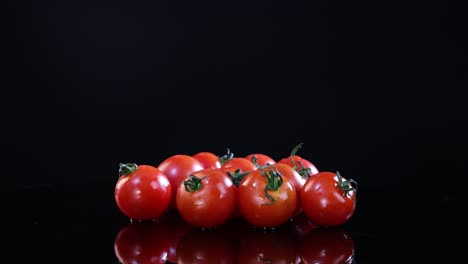 cherry tomatoes rotate on a glossy black surface under bright lighting, creating a vibrant and fresh visual effect