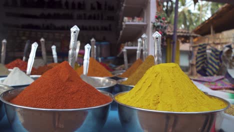 close up overview across lots of vibrant colourful herb - spice powders in outdoor store market scene in goa india