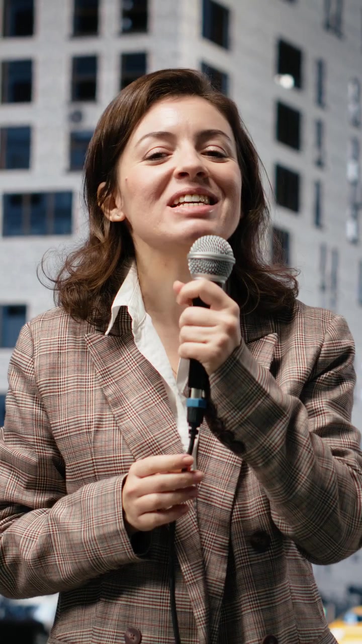 Video verticale: Reporter donna sorridente con microfono che presenta notizie sul traffico cittadino intenso