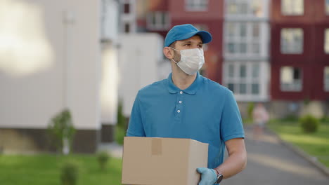 an young mailman courier with a protective mask and gloves is delivering a parcel directly to a customer home with safety. concept of courier home delivery e-commerce shipping virus covid