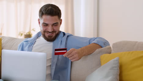 man shopping online with credit card on laptop at home