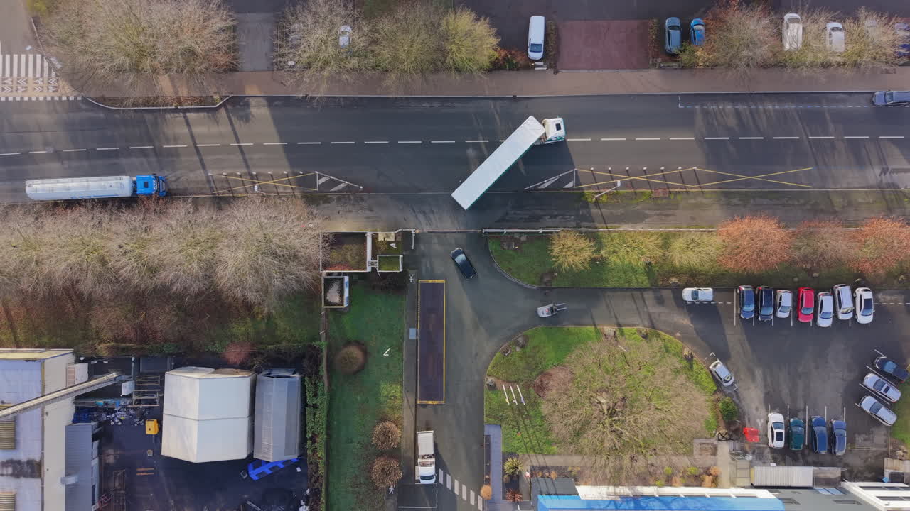 Top-down drone view of a semi truck leaving an industrial factory, showing logistics flow, freight transport and supply chain operations