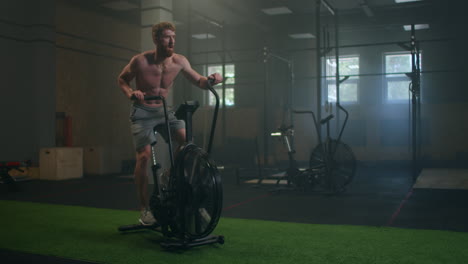 Man-exercise-bike-gym-cycling-training-fitness.-Fitness-male-using-air-bike-cardio-workout.-Athletic-girl-using-exercise-equipment-in-the-modern-dark-gym.
