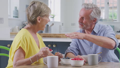 Pareja-De-Jubilados-Sentados-Alrededor-De-La-Mesa-En-Casa-Desayunando-Saludablemente-Con-Fruta-Fresca-Juntos