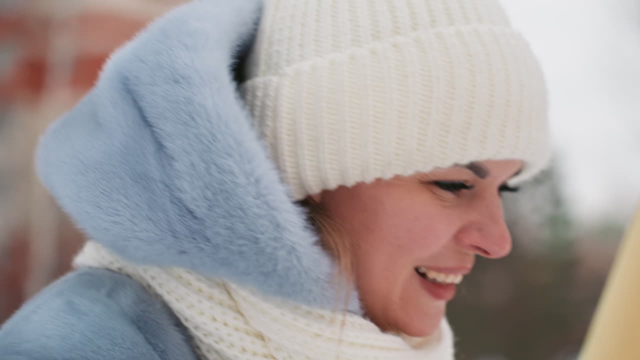 Donna caucasica con sciarpa invernale pensierosa, primo piano di profilo in un cortile urbano innevato con sullo sfondo edifici in mattoni, berretto di lana e cappotto di lana, respiro visibile, luce fredda e attenuata, espressione pensierosa.
