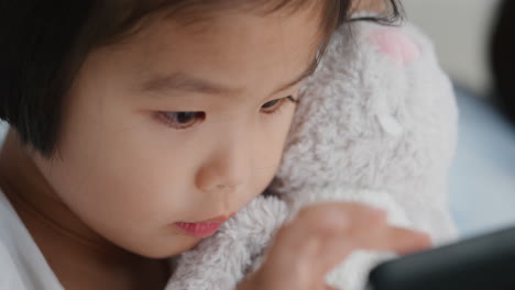 가족과 함께 태블릿 컴퓨터를 사용하는 귀여운 작은 아시아 소녀는 터치 스크린 장치에서 게임을 즐기고 집에서 함께 휴식을 취합니다 4k