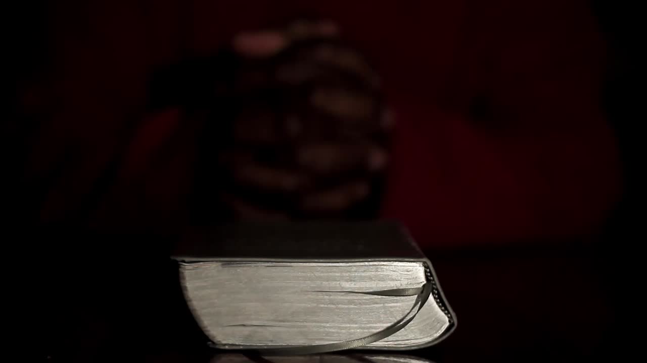 rezando a dios con las manos junto con la biblia y el hombre cruzado del caribe rezando con fondo negro almacen de video