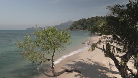 Aerial-backwards-dolly-descending-tropical-beach-in-Koh-Chang,-Thailand-jungle-mountains