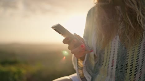 Close-up-of-blonde-young-woman-using-smartphone-in-slow-motion-at-sunset