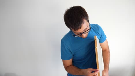 Joven-Instalando-Tapones-De-Madera-En-Un-Tablón-Blanco-De-Muebles,-Plano-Frontal-Medio