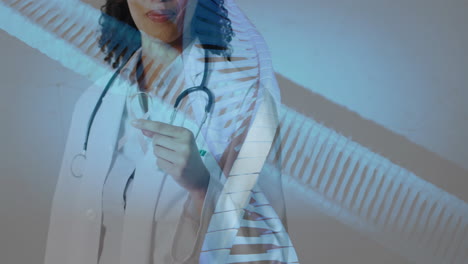 animation of dna strands over african american female doctor holding pink ribbon