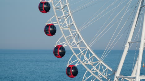 close-up sokcho eye passenger cars moving up against sea background while ferris wheel turns in sokcho city, south korea