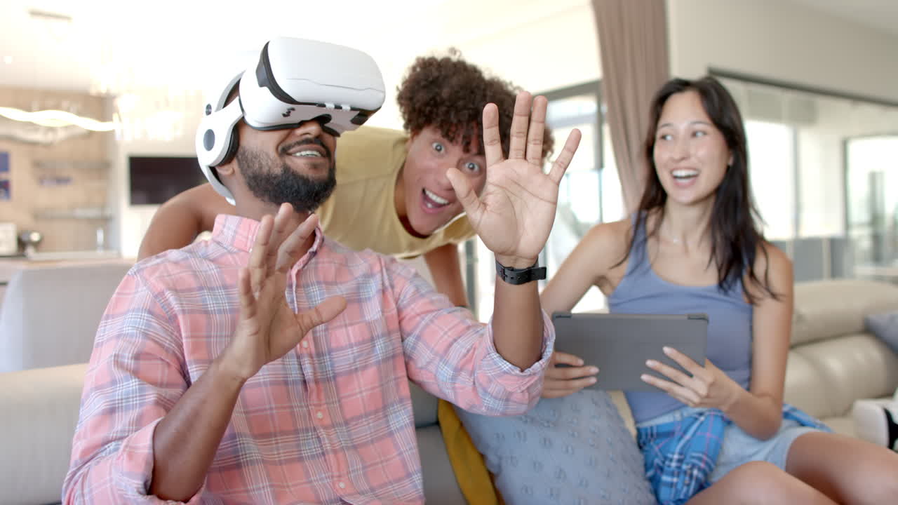Using VR headset, man interacting with virtual world, Diverse friends watching and laughing