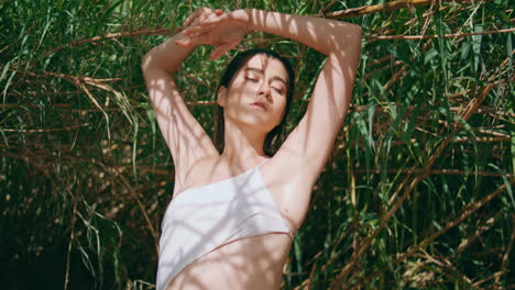 swimsuit model moving hands at sunny bamboo nature closeup. woman touching skin