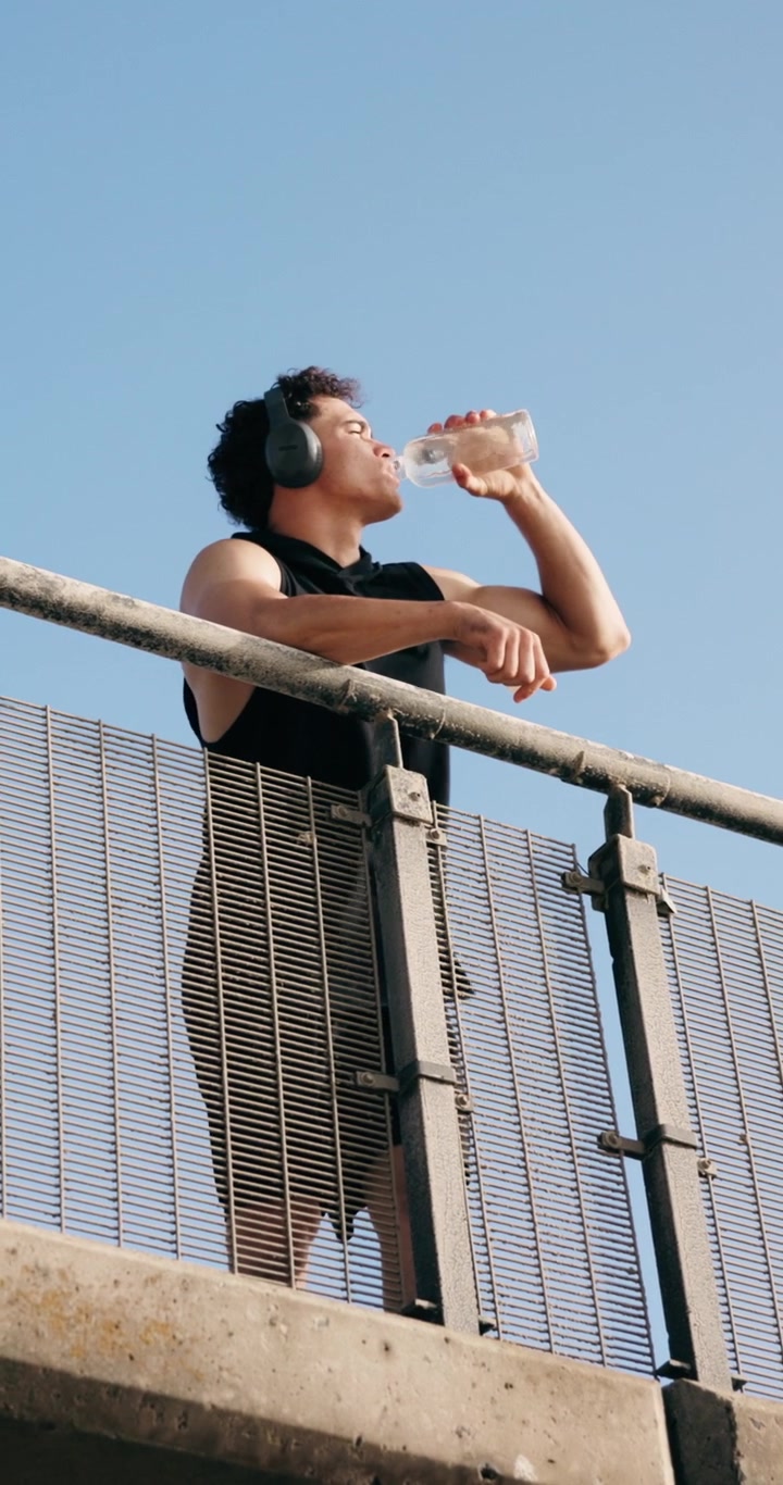 Young Man Drinking Water After Workout on Bridge