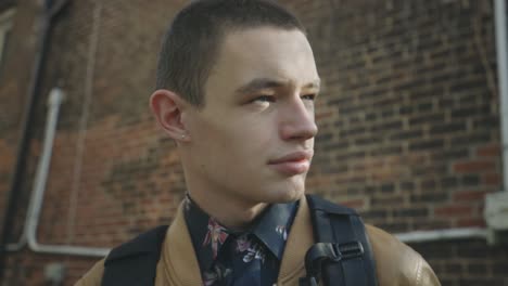 Attractive-Man-Looking-Away-Standing-Near-An-Old-Brick-Building---Low-Angle-Shot,-Slow-Motion