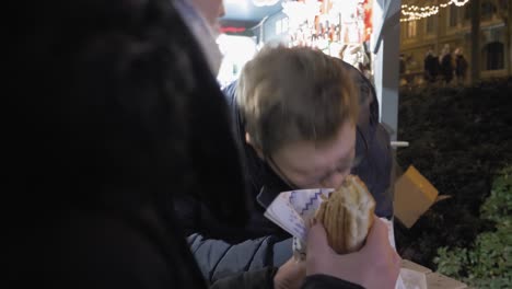 mother and son enjoy hot sandwiches on evening outside, family time together. christmas time.